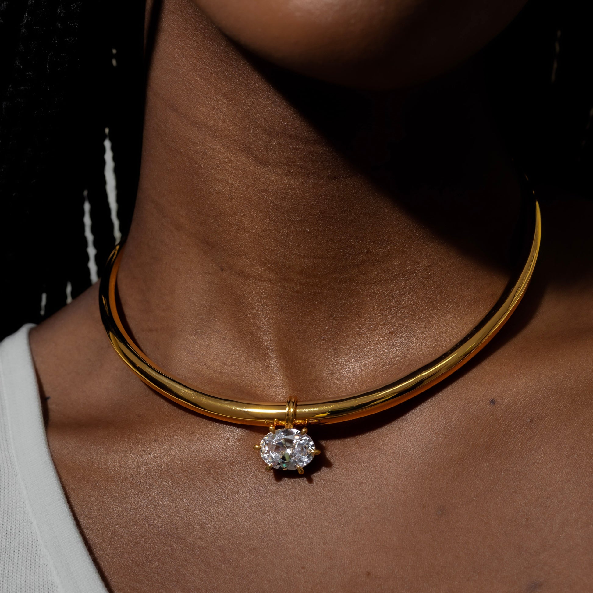 Gold necklace with a diamond pendant worn by a person