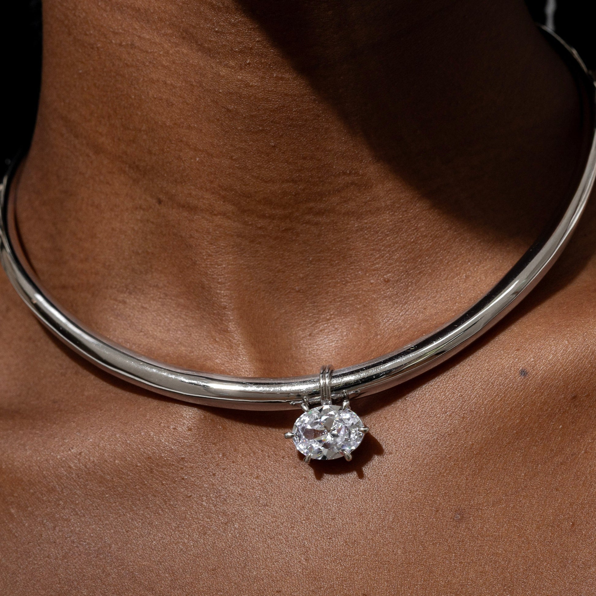 Silver necklace with a round pendant on a person's neck